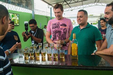 copos de tequila caindo dentro de copos de cerveja, amigos do noivo olhando'