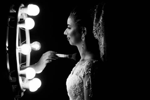 fotografia da noiva iluminada por um ring light, mão da maquiadora fazendo o retoque da maquiagem durante o making of do casamento realizado em Araçuaí, Minas Gerais.'