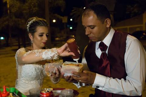 Noiva colocando ketchup no cachorro quente do noivo, durante ensaio fotográfico pós casamento realizado na cidade de Araçuaí, Minas Gerais'