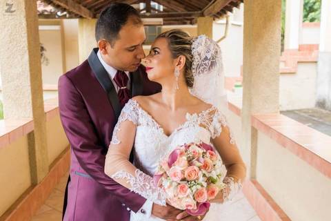 Fotografia dos noivos abraçados, se olhando, enquanto a noiva segura o buquê'