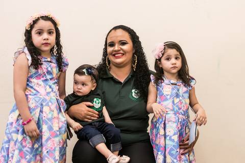 Formanda posando para a foto com suas 3 filhas'