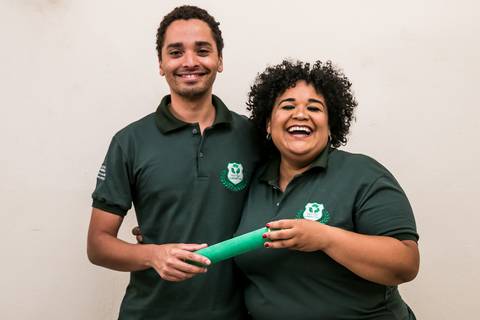 Formanda sorrindo segurando do diploma junto ao professor'