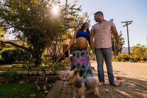 Casal gestante passeando com os cachorros na calçada'