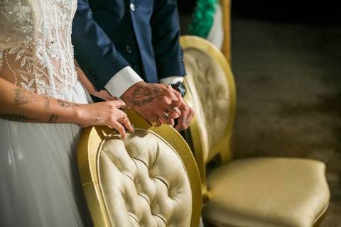 fotografia das mãos dos noivos, dadas, em cima de uma cadeira durante cfasamento.'