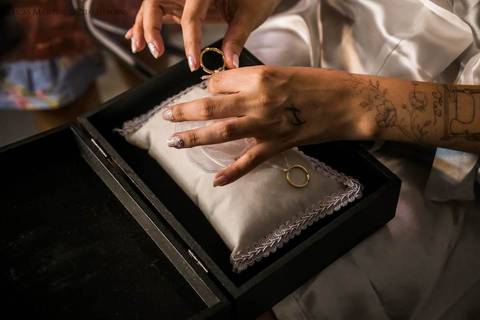 fotografia em close, das mãos da noiva mexendo na caixinha de alianças.'