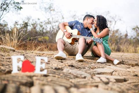 fotografia de casal sentados no chão com um violão'