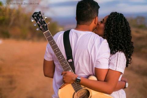 fotografia de casal com violão, a namorada da um beijo no rosto do rapaz.'
