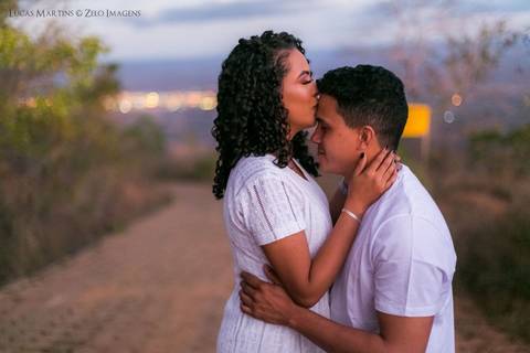 fotografia da mulher dando um beijo na testa do seu namorado em estrada de terra, durante ensaio fotográfico de casal.'