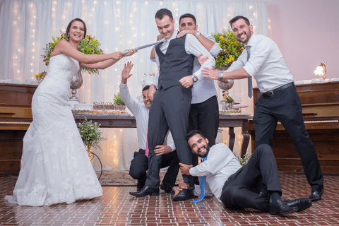 noiva puxando noivo pela gravata padrinhos segurando os pes do noivo'