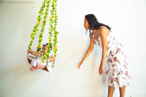 mão balançando filha num balanço cheio de flores'