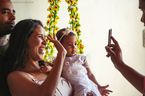 Pai, mãe e filha falando com familiares via chamada de vídeo'
