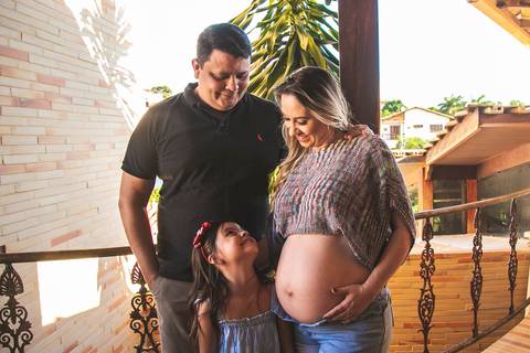 gestante e sua familia posando na sacada da casa'