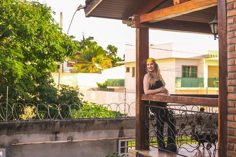 gestante posando na sacada da casa de tijolinhos com um conjunto preto e uma bandana'