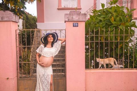 Gestante posando em frente uma casa antiga com um gatinho '