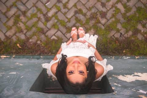 gestante posando com um vestido branco encostada em uma parede'