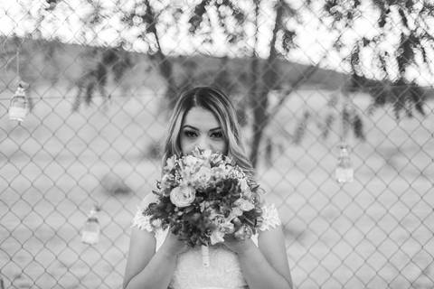 Foto em preto e branco de noiva segurando seu buquê. '
