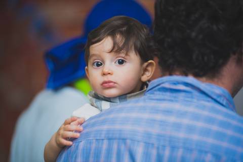 Bebê observa se sendo fotografado no colo do pai'