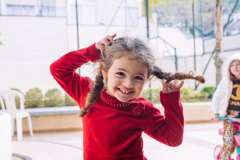 Menina de trança observa sorridente'