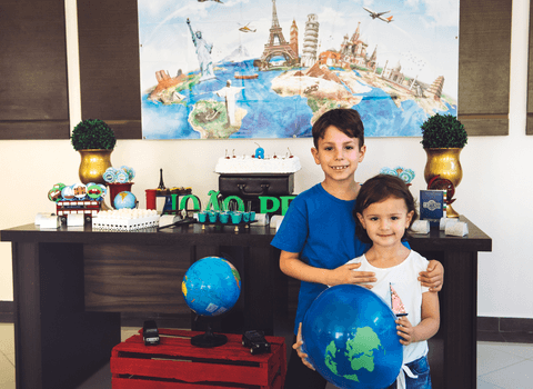 Irmãos abraçados para foto do aniversariante em frente a mesa do bolo'