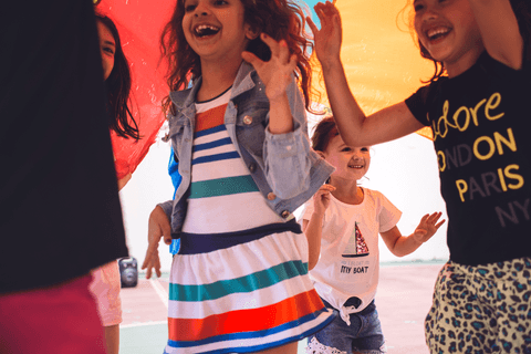 Embaixo do pano colorido , meninas brincam com a equipe de recreação infantil'