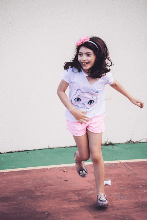 Menina veste camiseta com gatinha e da um salto em aniversário infantil'