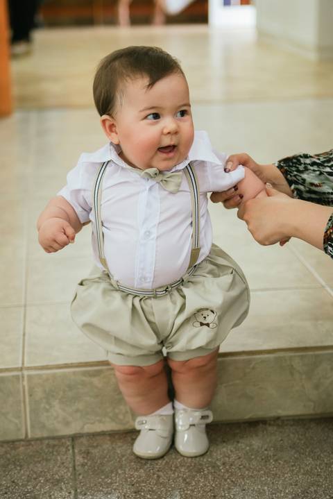 Roupa de batizado com bebê mostrando sua bermuda, suspensório, gravata borboleta'