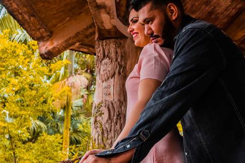 Ensaio pré wedding de casal. O rapaz está atrás da moça com o rosto sobre seu ombro. A moça está
vestida com um vestido rosa salmão e o rapaz com uma jaqueta jeans. '