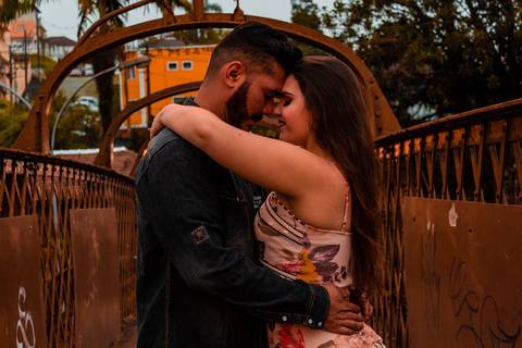 Casal se abrasando e se beijando em uma passarela marrom antiga.'