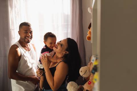 família brincando no quarto do bebê, todos estão rindo '
