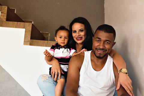 família sentada em escada de casa, o bebê está no colo da mãe'