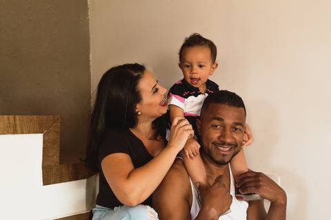 família brincando na escada de casa, o bebê está sentado nas costas do pai '