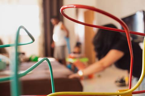 pai brincando com filho pequeno na sala, ele está empurrando a criança em um carrinho '