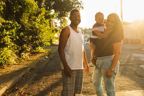 família se abraçando, estão na rua e está um por do sol '
