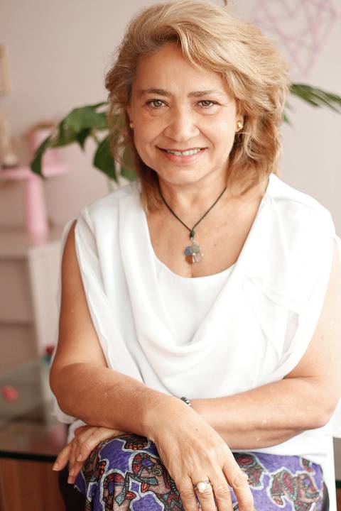 Retrato de Dulce Marques com um background em tons vendes, beges e um rosa suave na sala do Ventre Terapias Femininas clicado pela fotógrafa Marina Guimarães em Recife Pernambuco'