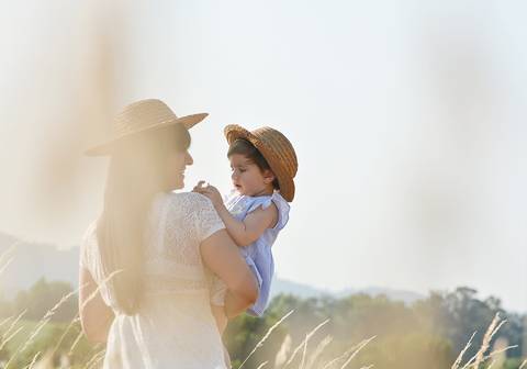 mãe com menina ao colo no campo'