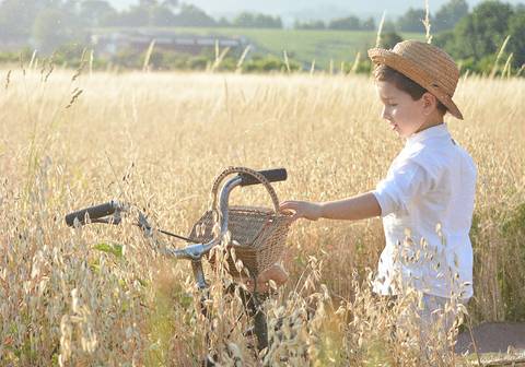 menino de bicicleta e chapéu de palha no campo'