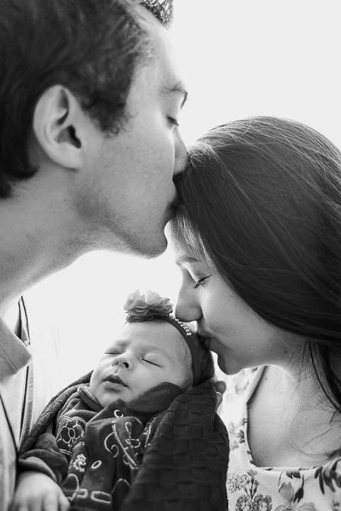 Beijo de Família - Papai na testa da mamãe e mamãe beijando a cabeça da filhinha em preto e branco'