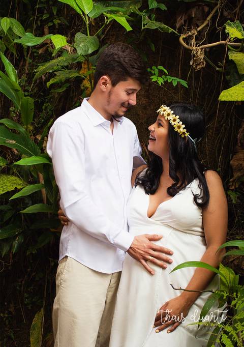 Fotografia de gestante casal segurando a barriga se olhando e sorrindo pela fotógrafa Thais Duarte'