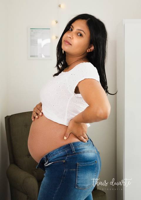 Fotografia de gestante morena com mão na barriga foto por Thais Duarte'