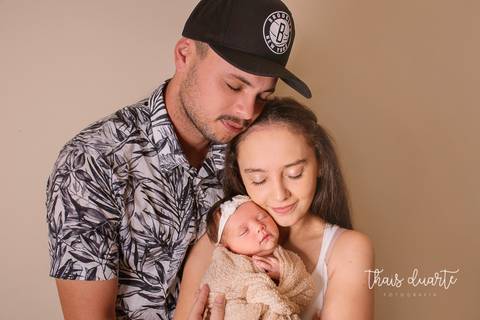 Fotografia de sessão newborn pai e mãe segurando bebê no colo pela fotógrafa Thais Duarte'