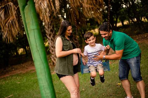 pais brincando como filho no balança durante ensaio gestante'