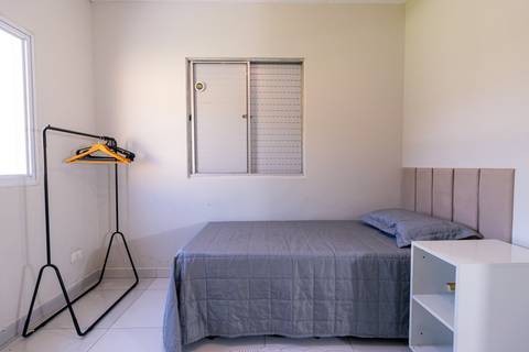 Fotografia profissional de uma casa no bairro Jardim Samambaia, em Praia Grande, SP, pelo fotógrafo profissional de imóveis Fernando Freire, foto para anúncio no Airbnb e Booking. Ambiente do quarto com mobília.'