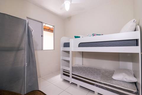 Fotografia profissional de uma casa no bairro Jardim Samambaia, em Praia Grande, SP, pelo fotógrafo profissional de imóveis Fernando Freire, foto para anúncio no Airbnb e Booking. Ambiente do quarto completo e mobiliado.'