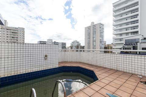 Fotografia profissional de uma cobertura no bairro Canto do Forte, em Praia Grande, SP, pelo fotógrafo profissional de imóveis Fernando Freire, foto para anúncio de apartamento no Airbnb e QuintoAndar. Ambiente da varanda com churrasqueira e piscina.'