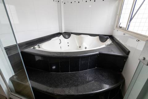 Fotografia profissional de uma cobertura no bairro Canto do Forte, em Praia Grande, SP, pelo fotógrafo profissional de imóveis Fernando Freire, foto para anúncio de apartamento no Airbnb e QuintoAndar. Ambiente da terceira suíte com banheira e armário.'