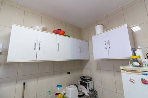 Fotografia Imobiliária profissional no bairro Vila Caiçara, feita por Fernando Freire, fotógrafo de imóveis na Praia Grande e Baixada Santista. Foto para anúncio em Airbnb da cozinha do apartamento mobiliado completa.'