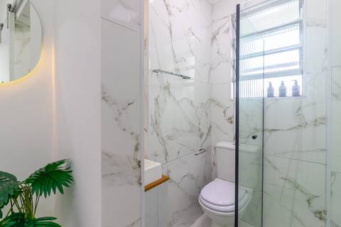 Banheiro moderno e bem iluminado em apartamento mobiliado para temporada – fotografia imobiliária em São Vicente.'