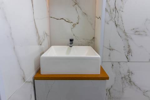 Banheiro moderno e bem iluminado em apartamento mobiliado para temporada – fotografia imobiliária em São Vicente.'