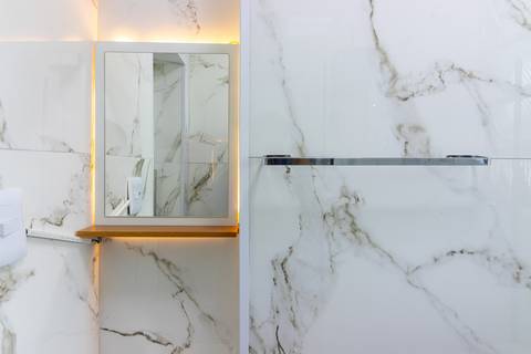 Banheiro moderno e bem iluminado em apartamento mobiliado para temporada – fotografia imobiliária em São Vicente.'