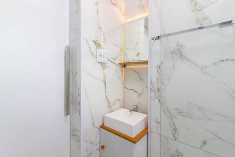 Banheiro moderno e bem iluminado em apartamento mobiliado para temporada – fotografia imobiliária em São Vicente.'